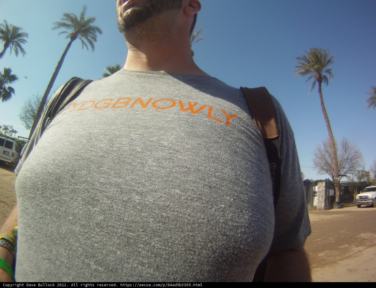 Man in Grey T-Shirt with Orange Logo Standing Outdoors