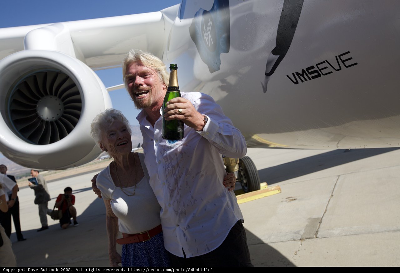 Richard Branson and companion stand next to their aircraft