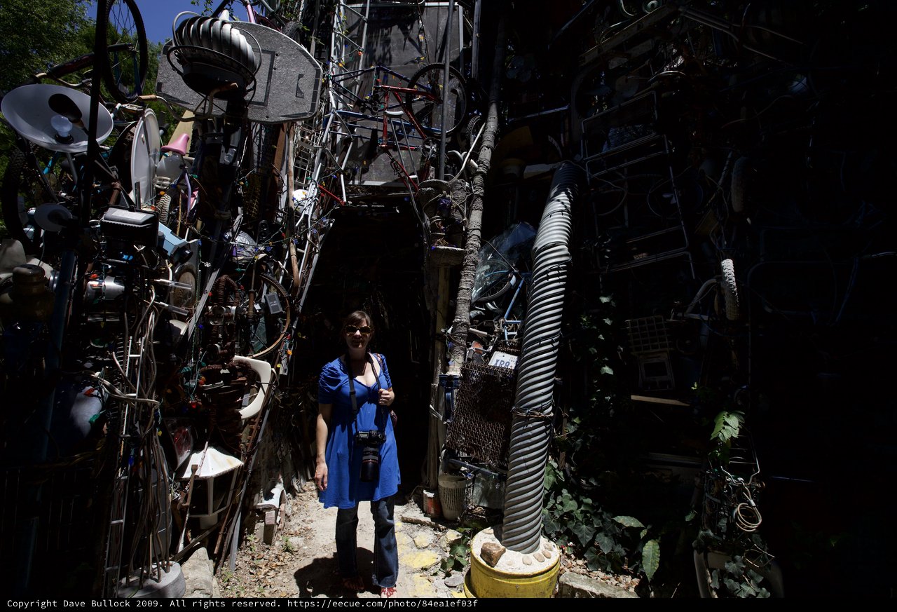 Woman Surrounded by Towering Walls of Salvaged Junk Art