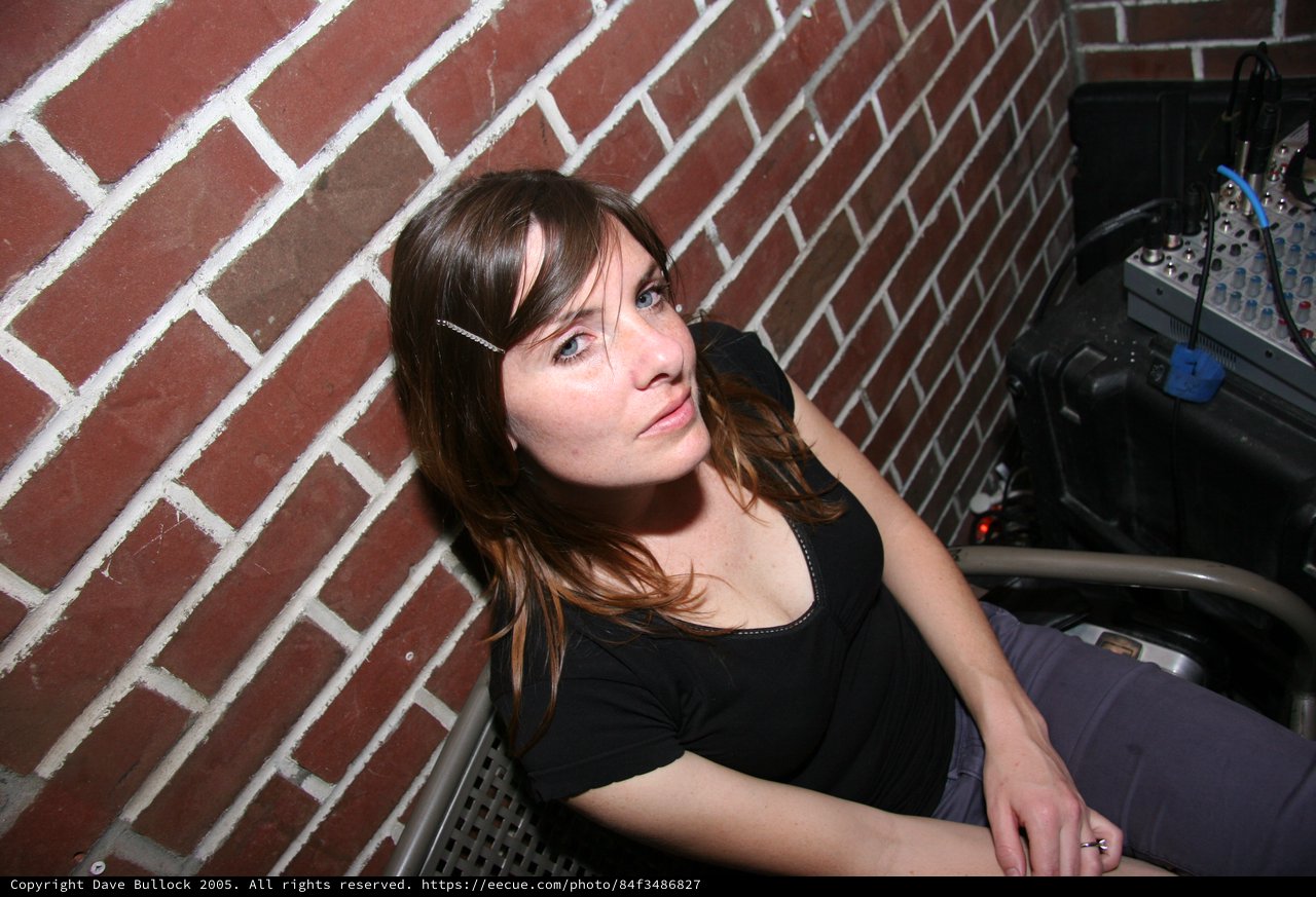 Young Woman Resting Against Brick Wall in Club