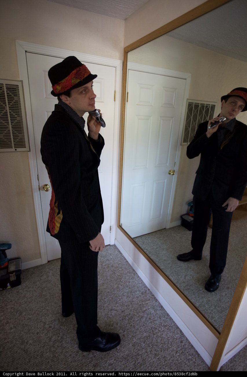 Man in Suit and Fedora Admiring Himself in Mirror