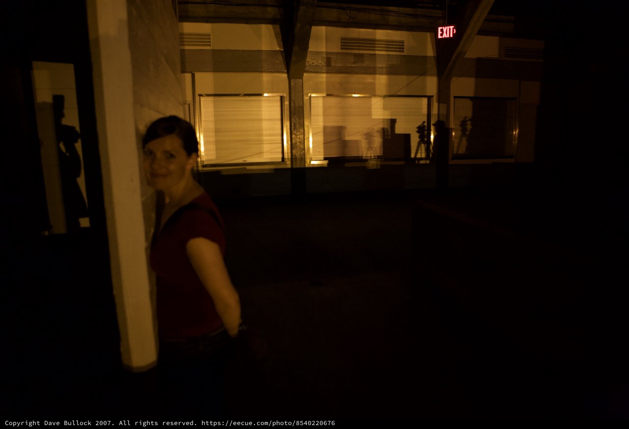 Woman in Red Smiles in Dimly Lit Warehouse Space