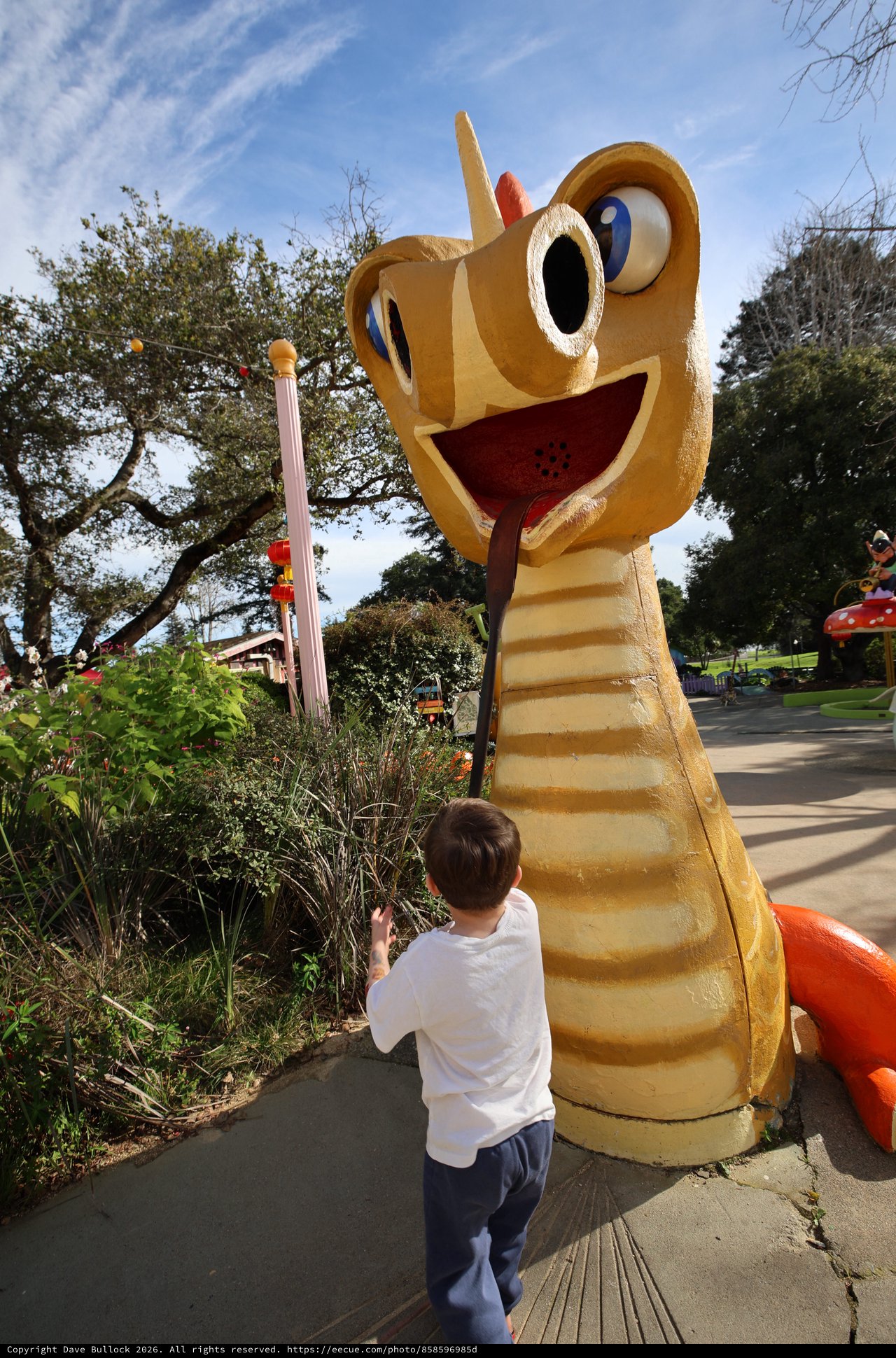 Child Encounters Whimsical Giant Snake Sculpture in Park