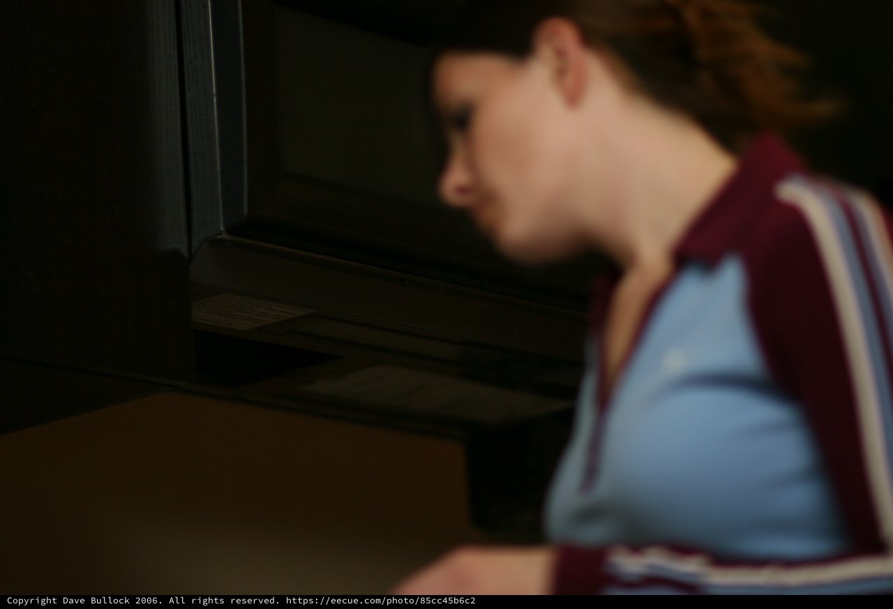 Young Woman Peering Into Dark Refrigerator at Night