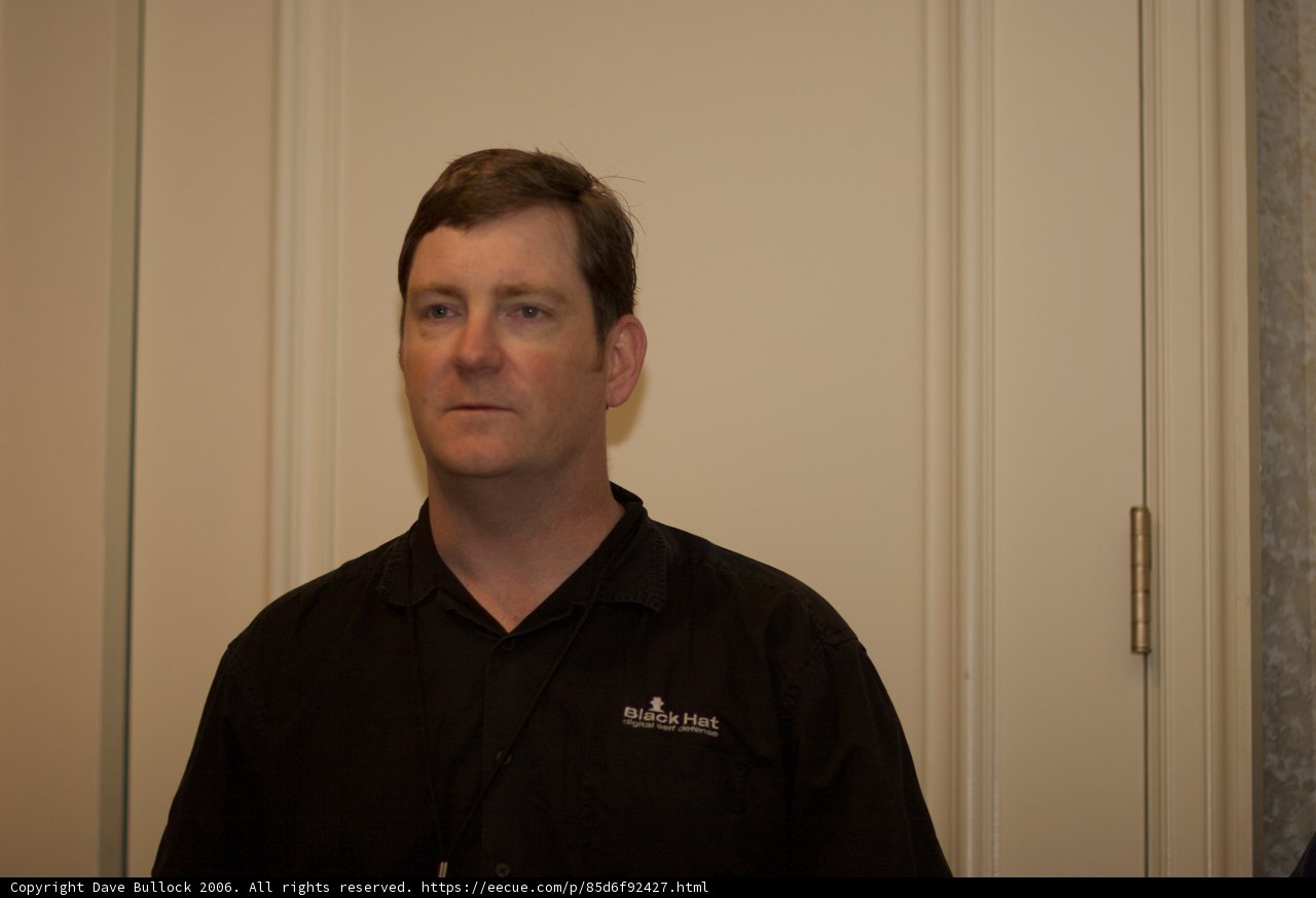 Black Shirted Man Poses in Front of White Door