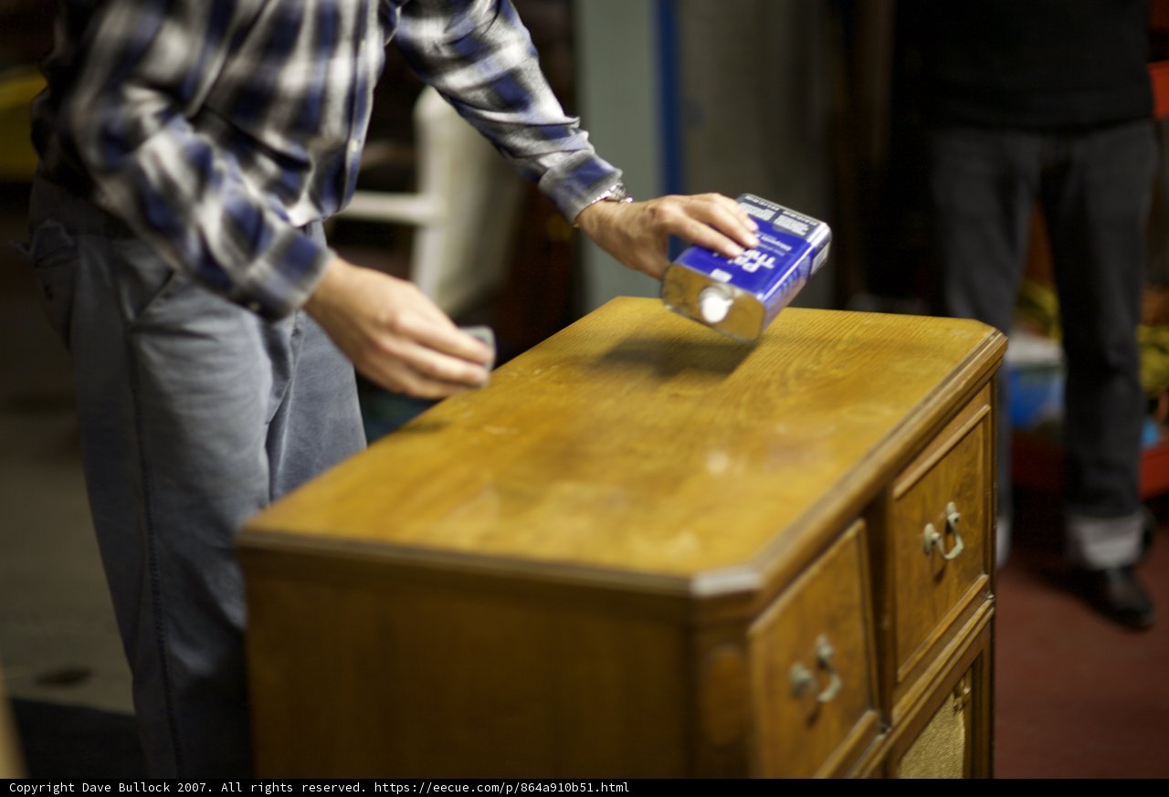 Cleaning a Wooden Dresser Caption: A man uses a can of paint to spruce up his old wooden dresser, revealing its natural beauty.