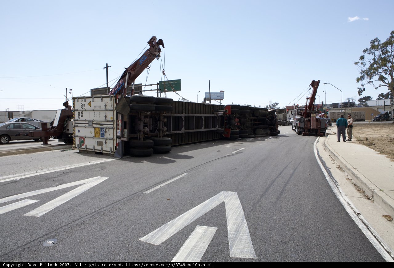 Crane lifting overturned truck on city street