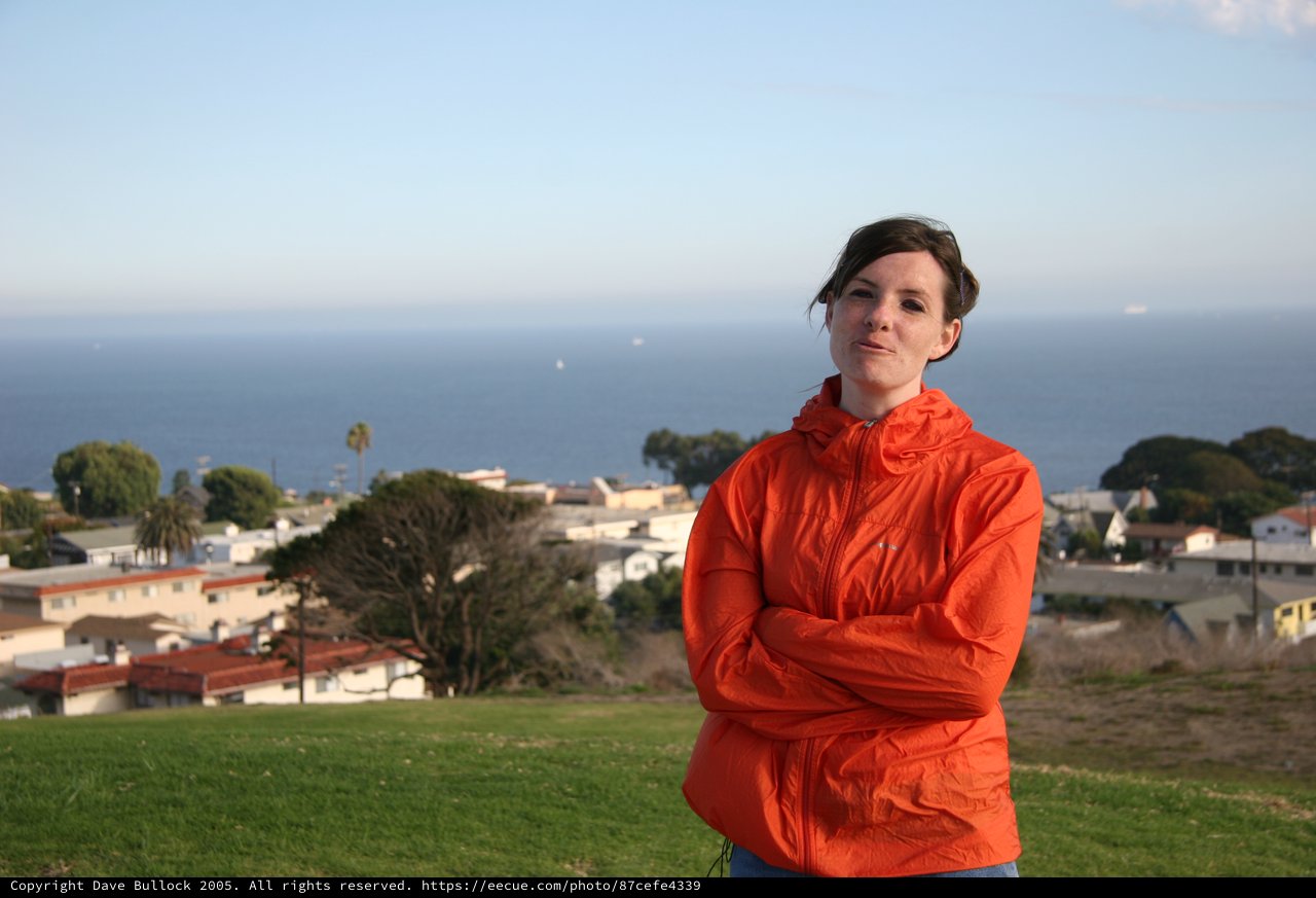 Woman in Orange Jacket Overlooking Coastal Town