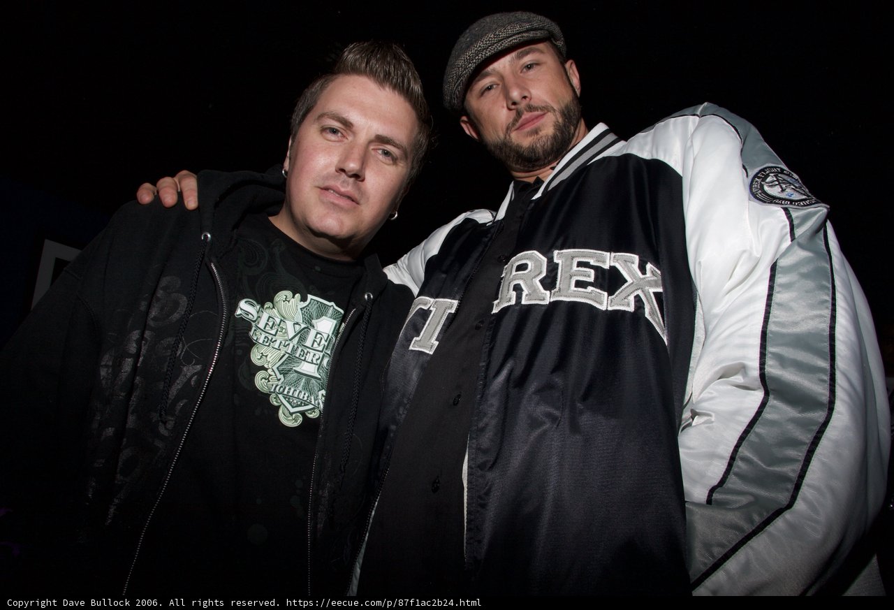Two Men in Coats Standing at a Party