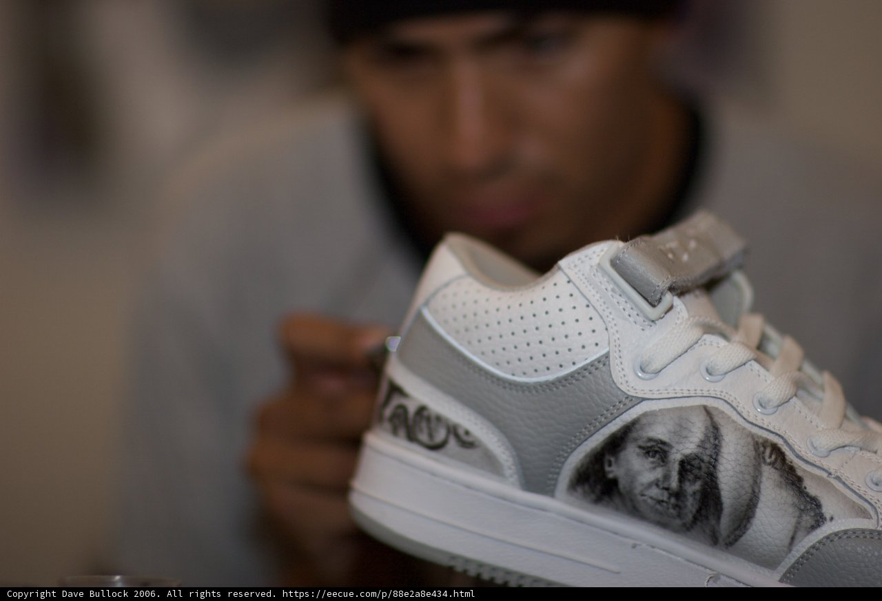 Man Holding Sneaker with Face on It