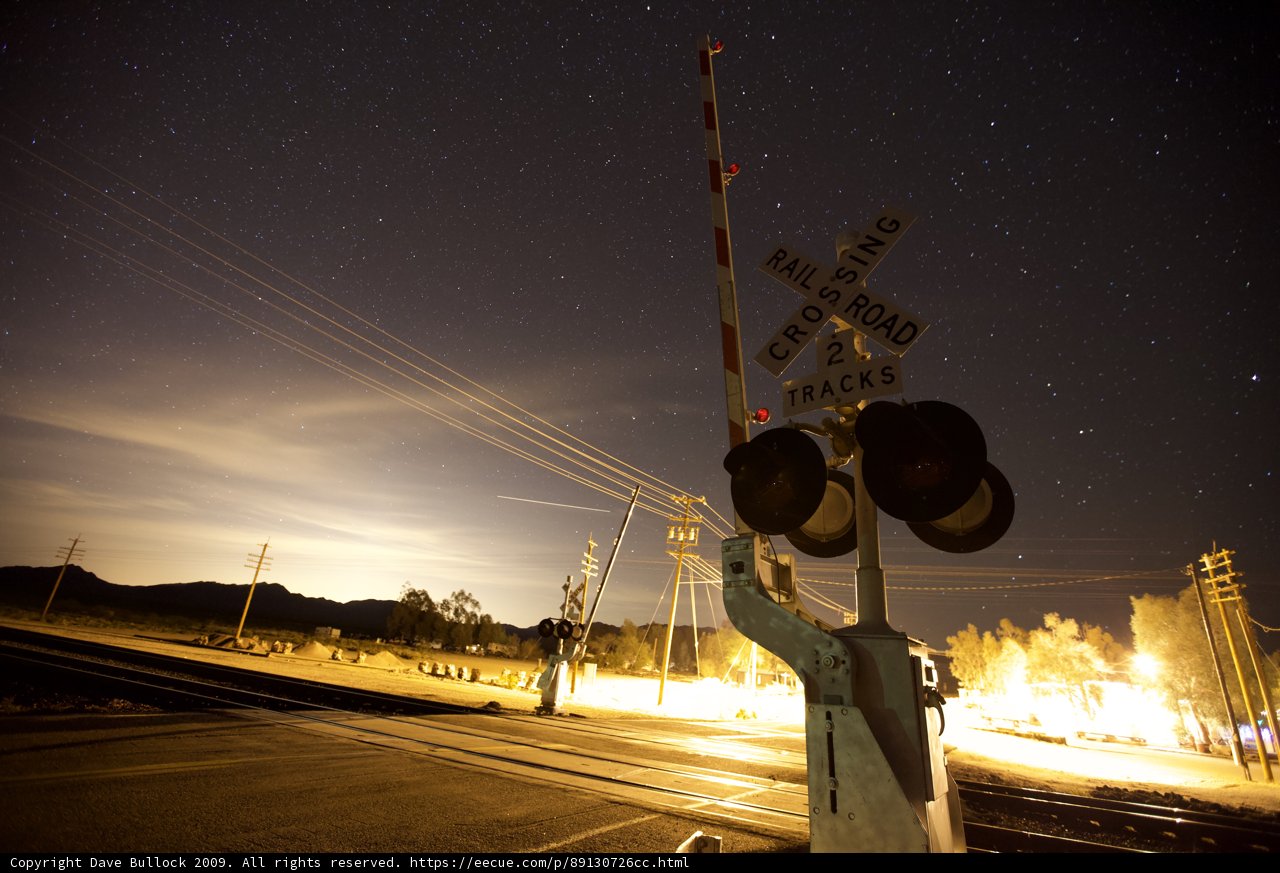 Nighttime Railroad Crossing under a Starry Sky