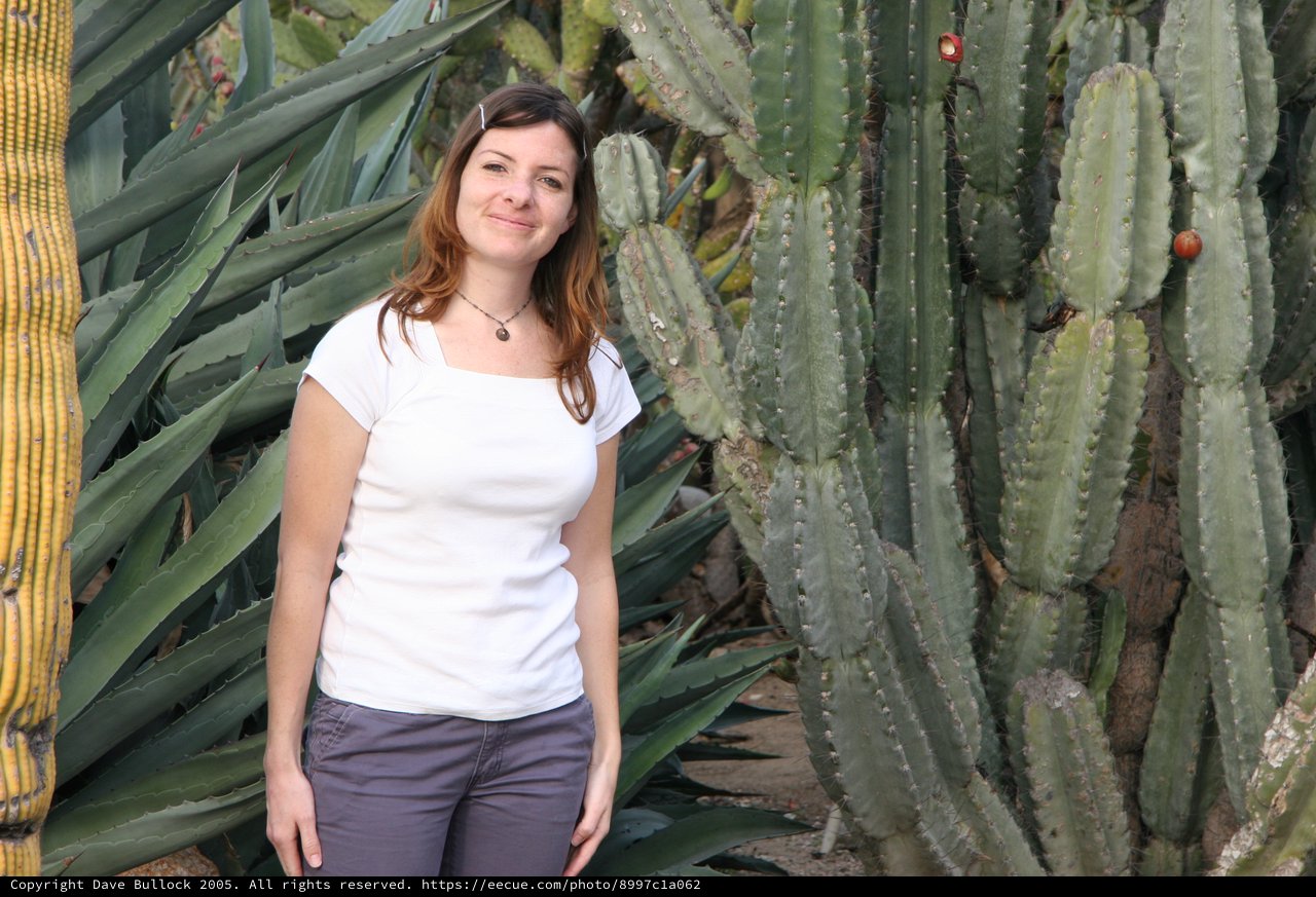 Woman Smiling Among Giant Cacti in Desert Garden