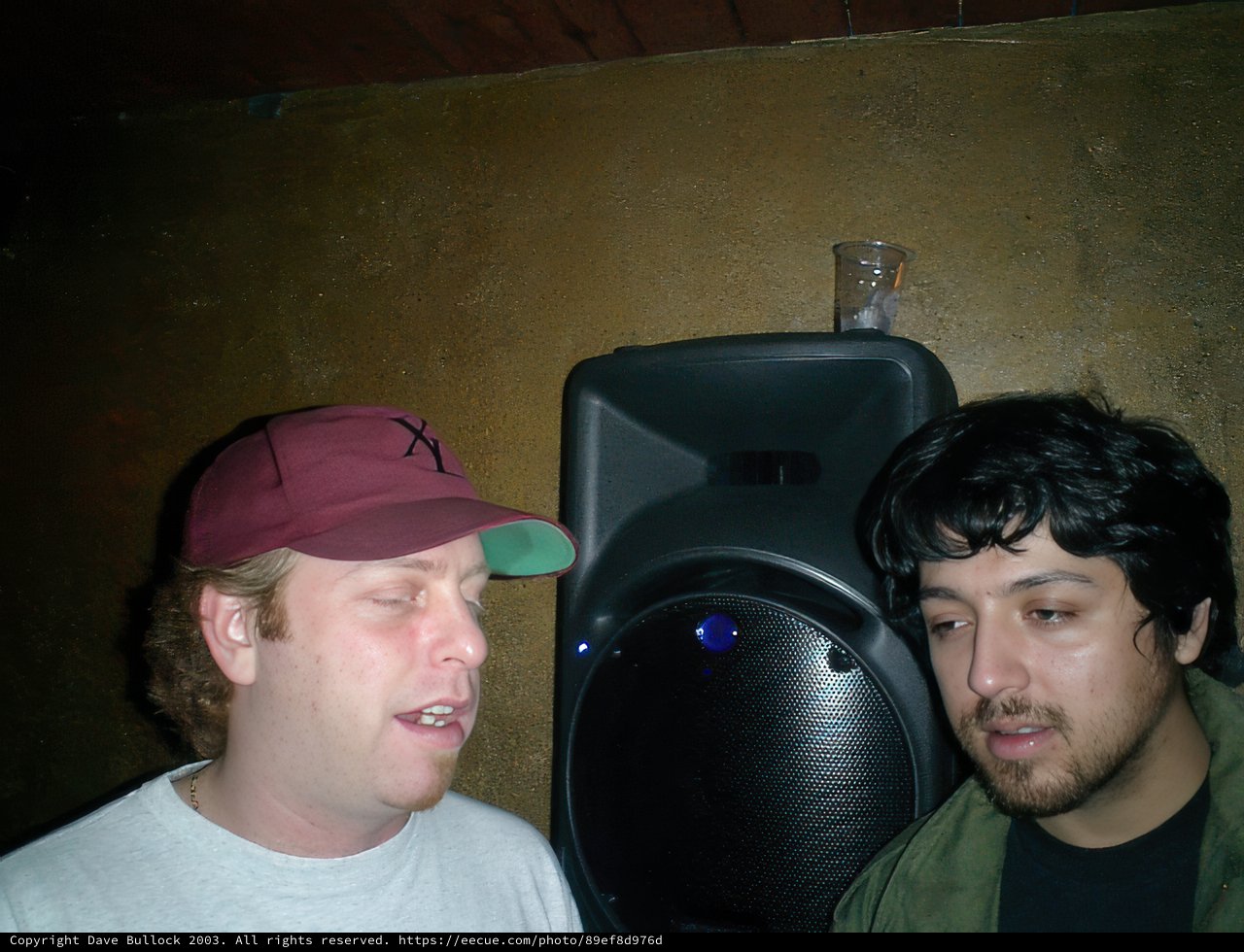 Two Men Stand Proud in Front of a Speaker