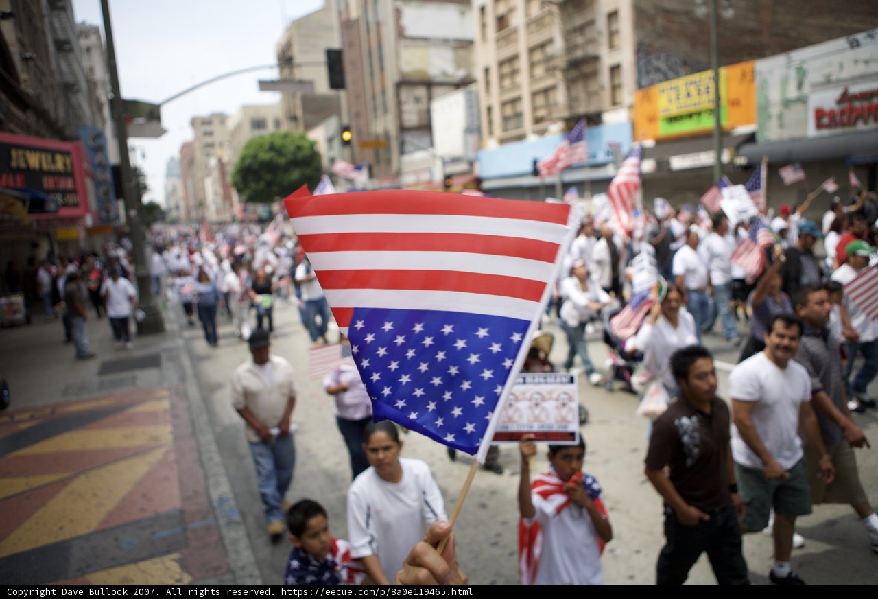 The Great American Walk Caption: Namita Toppo, Tanay Chheda, and a group of 25 people walk down a city street during the 2007 Great American Boycott, carrying an American flag and advocating for immigrant rights.