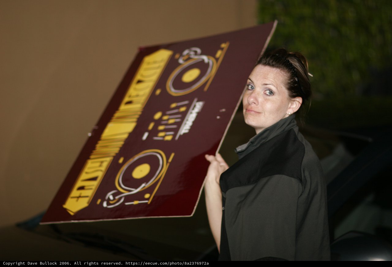Woman Hauling DJ Event Signage at Night