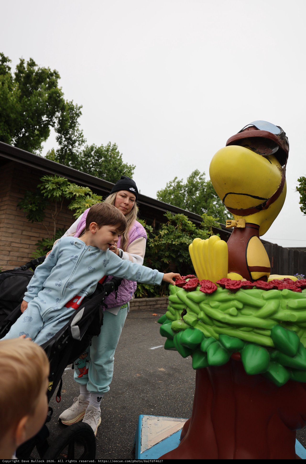 Child Touches Woodstock Statue at Theme Park