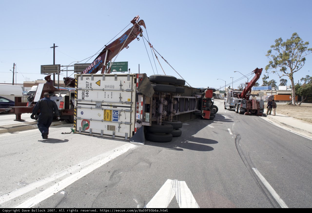 Crane lifting overturned truck on street
