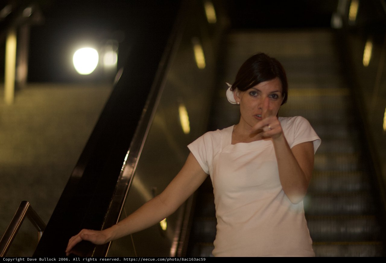 Woman on Escalator Gesturing in Dim Light