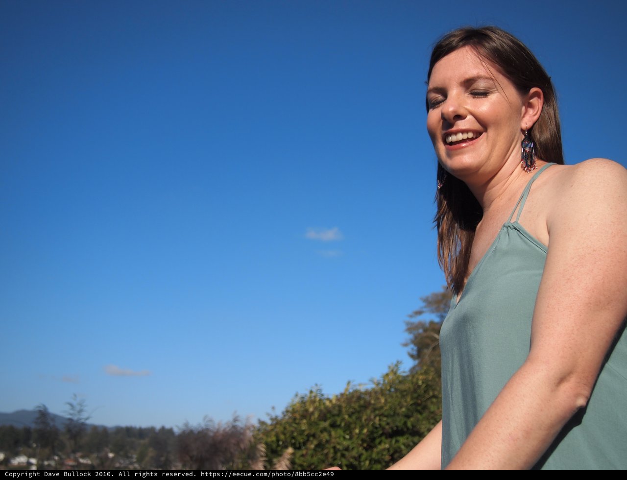 Joyful Woman Laughing Under Clear Blue Sky