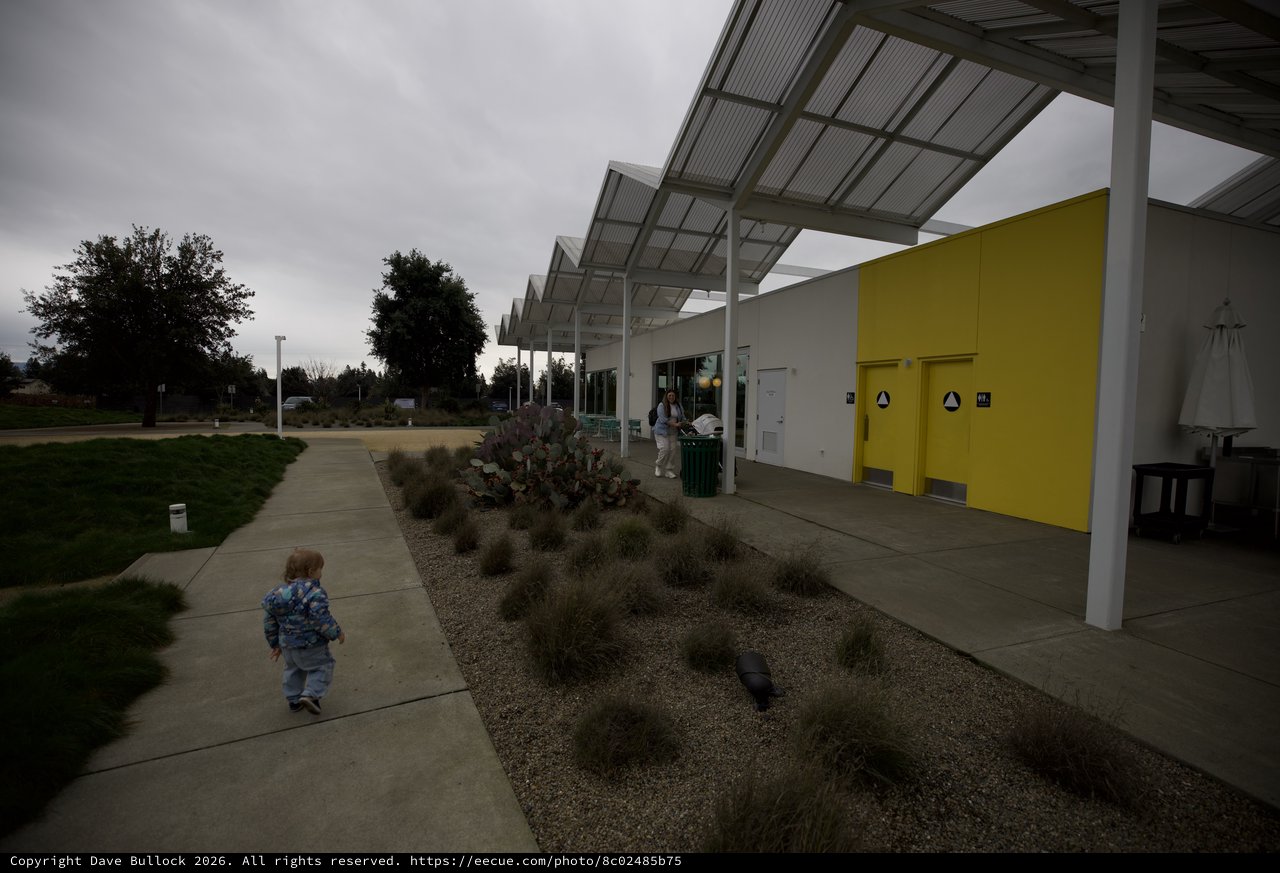 Child Exploring Modern Community Building on Overcast Day
