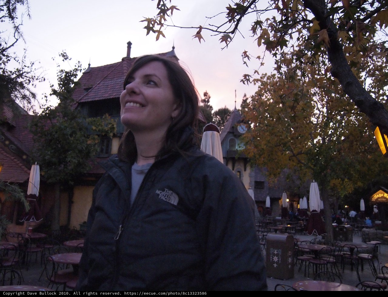 Smiling Woman at Dusk in Fairy-Tale Village Setting