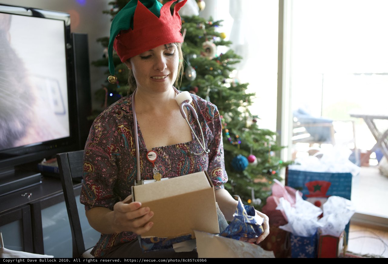 Joyful Elf Unwrapping Christmas Gifts at Home