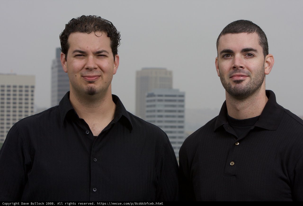 Two Men Smiling in Front of a Skyscraper