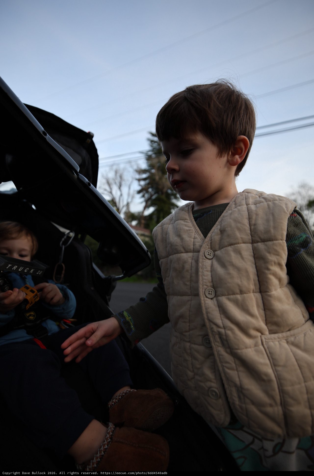 Young Boy Exploring Car Trunk on Suburban Street