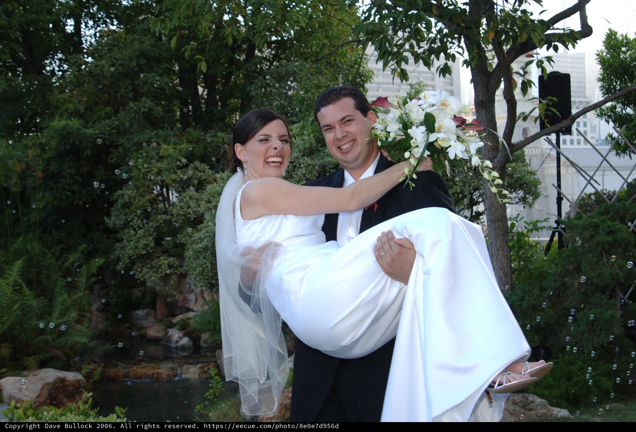 Joyful Groom Carries Laughing Bride in Garden