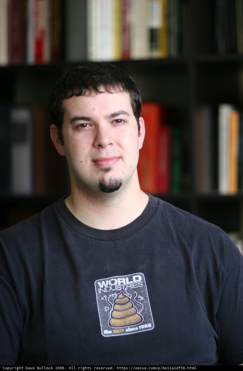 Man in Black Shirt Standing by Bookshelf