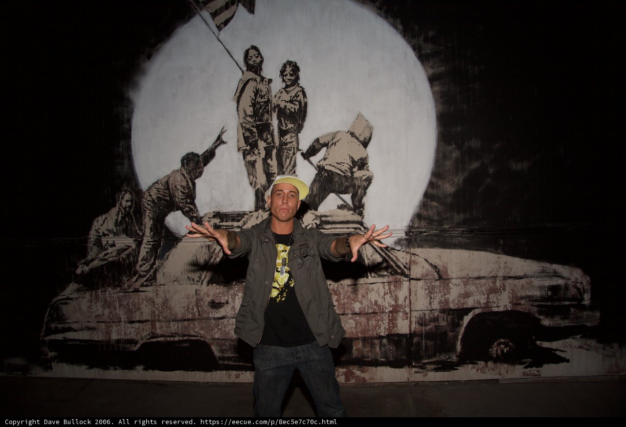 Man Poses in Front of Vibrant Mural with Classic Car