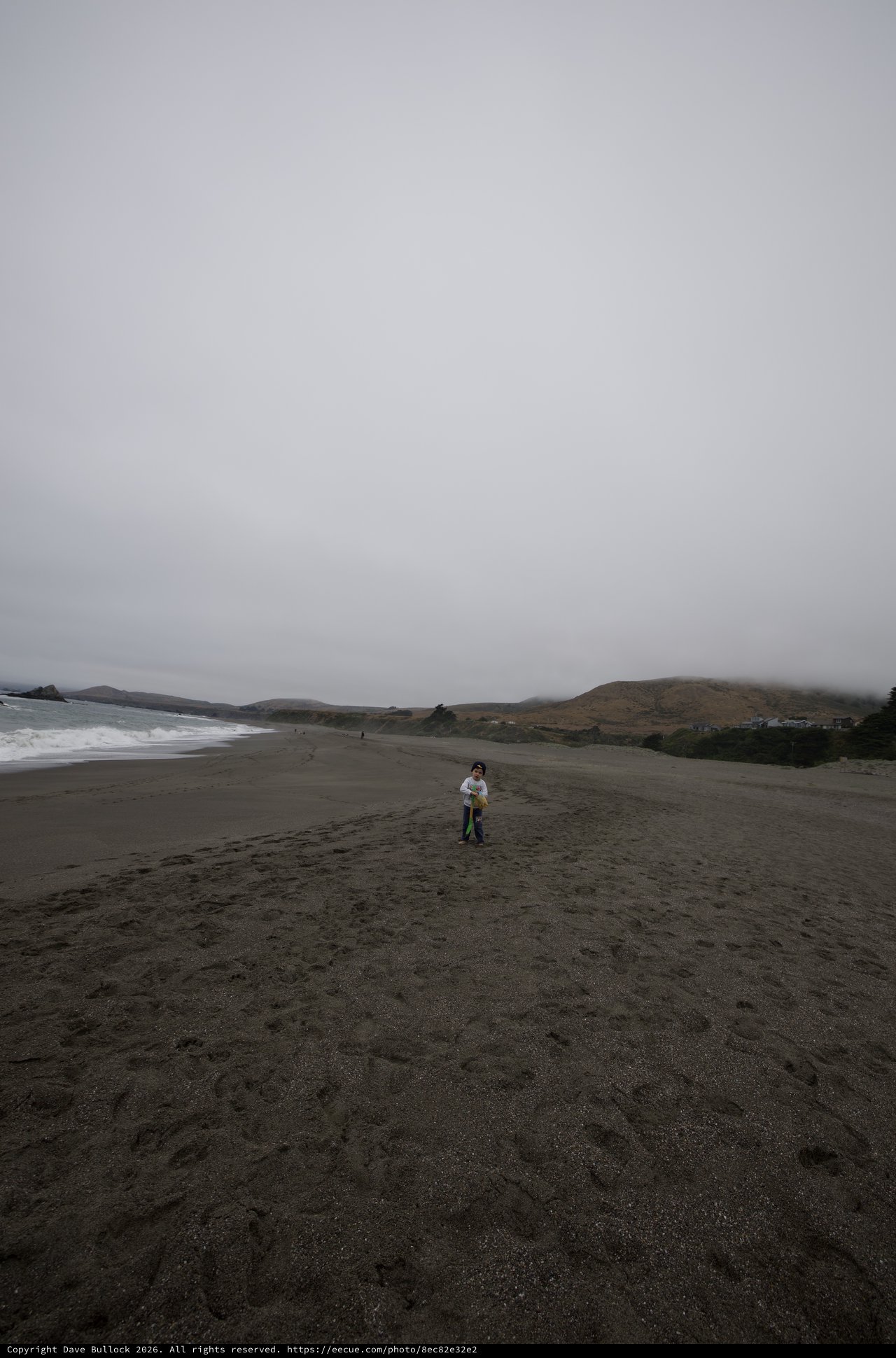 Small Child Standing Alone on Vast Foggy Beach