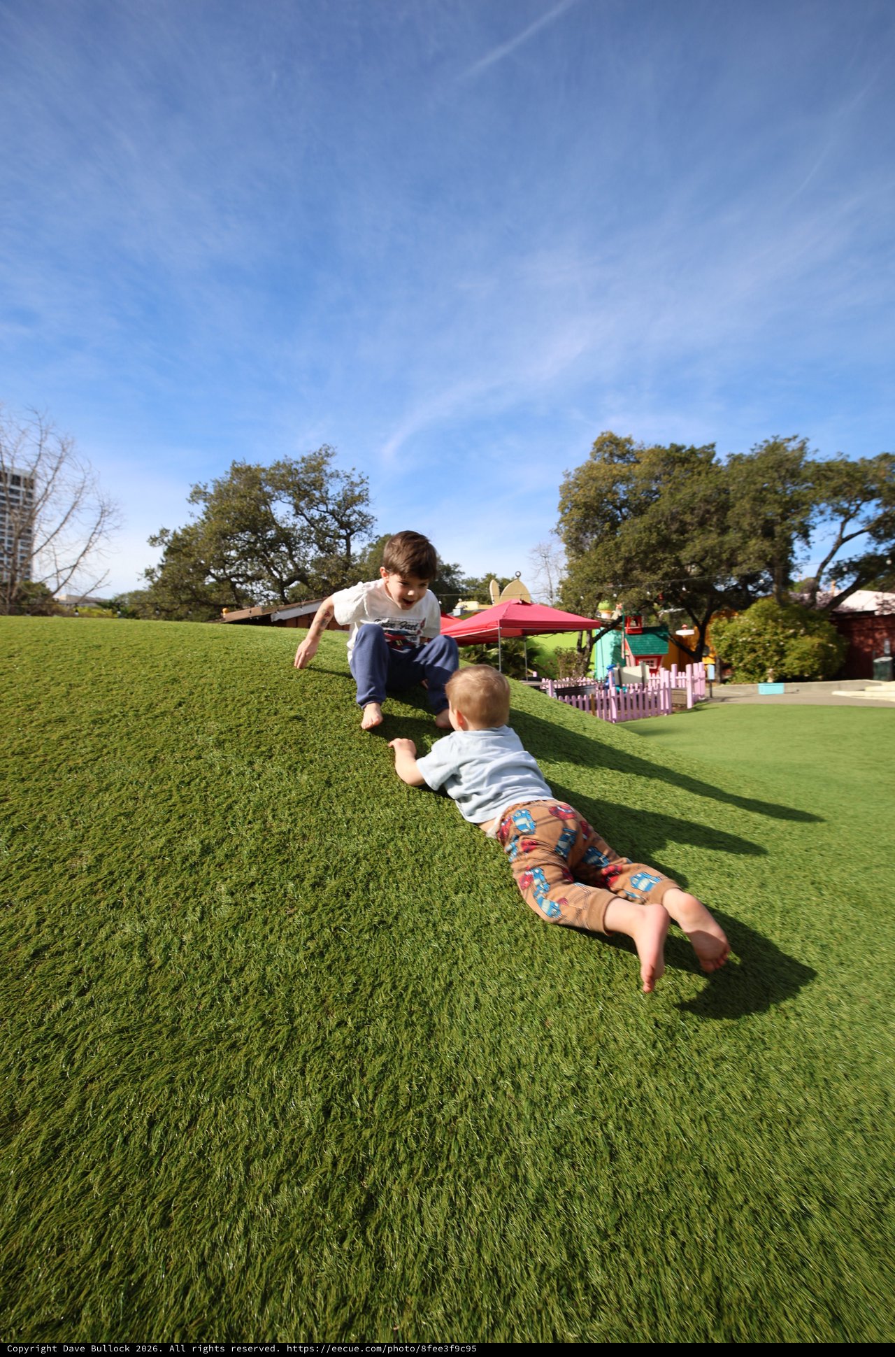 Brothers Playing Superman on Grassy Hill at Park