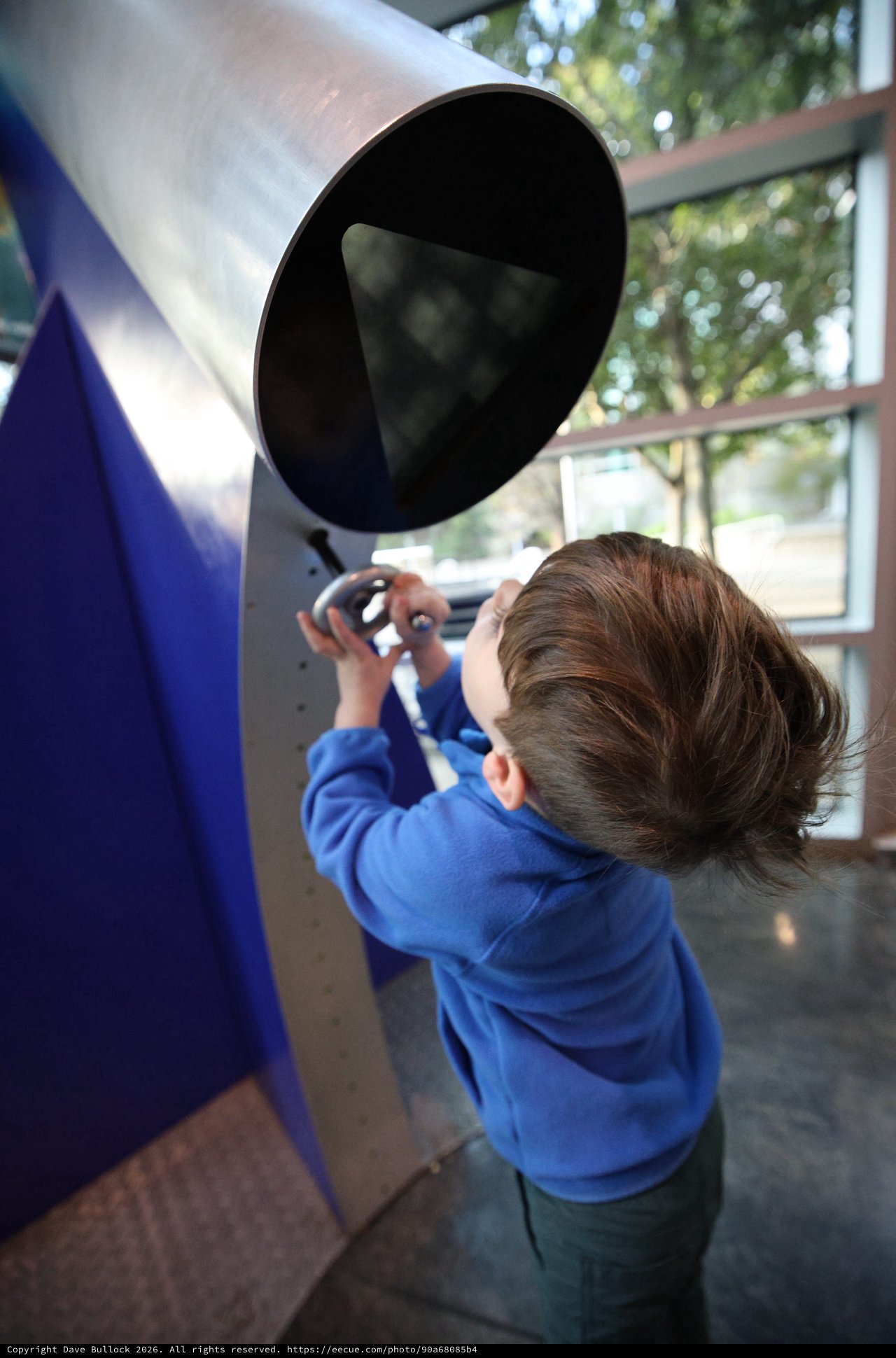 Young Child Exploring Interactive Telescope Exhibit at Science Center