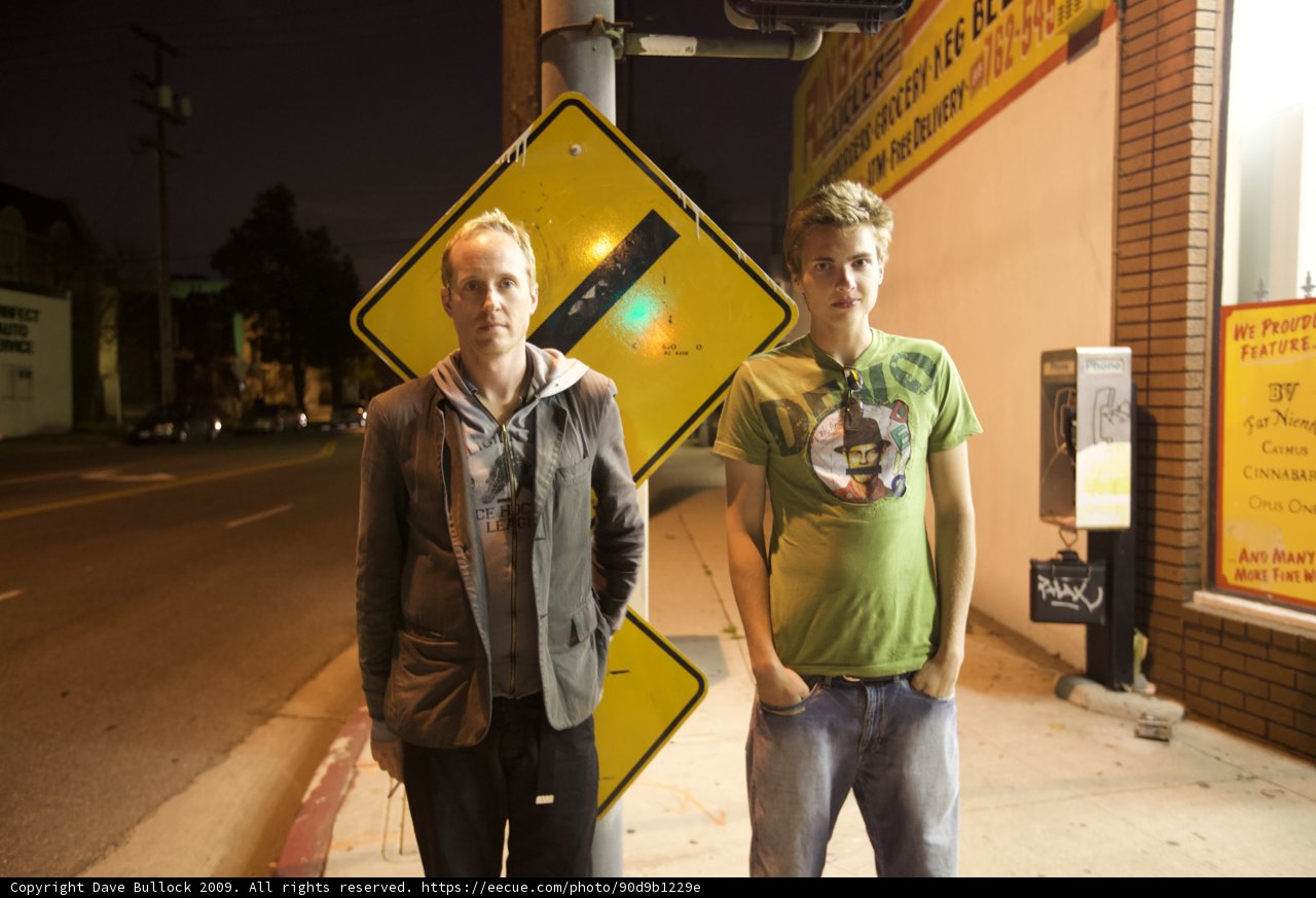 Two Men Standing by the Street Sign at Night