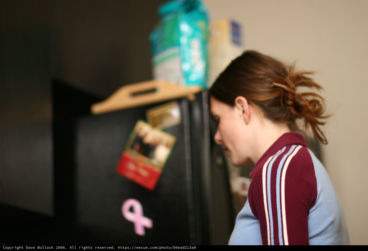 Woman Peering Into Open Refrigerator Late Night