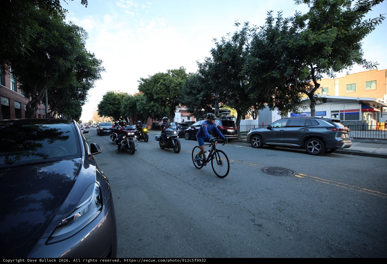 Urban Cyclist Shares Street with Motorcycles at Dusk