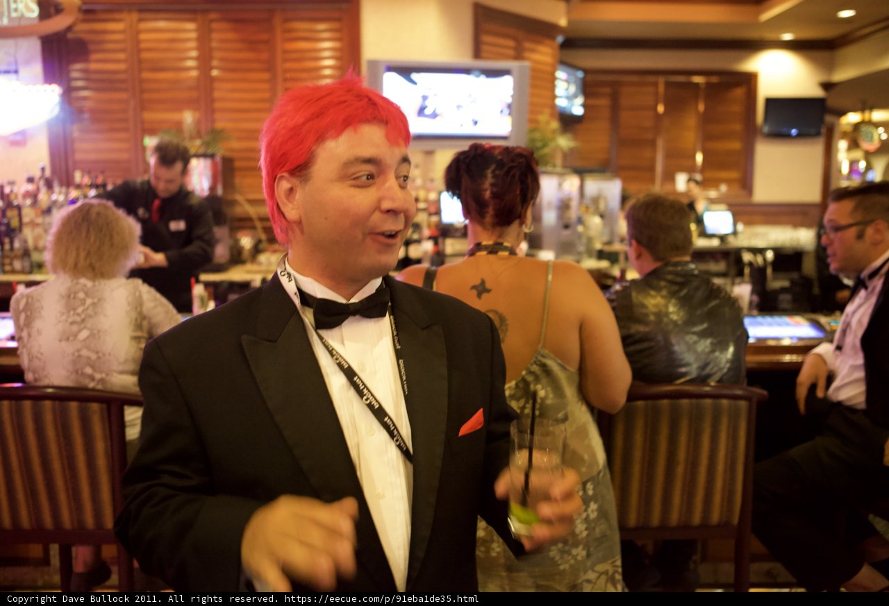 Red-Wigged Man in Tuxedo Enjoys a Drink at the Bar