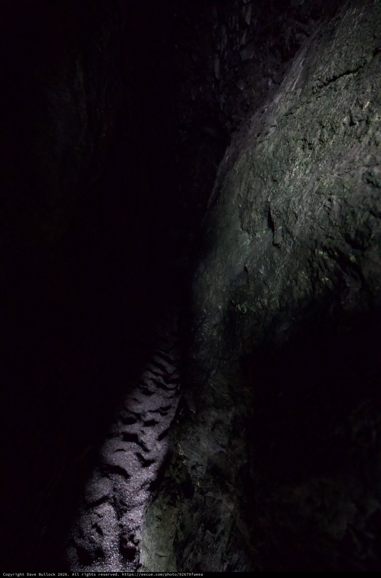 Dark Cave Passage with Sandy Floor and Rocky Wall