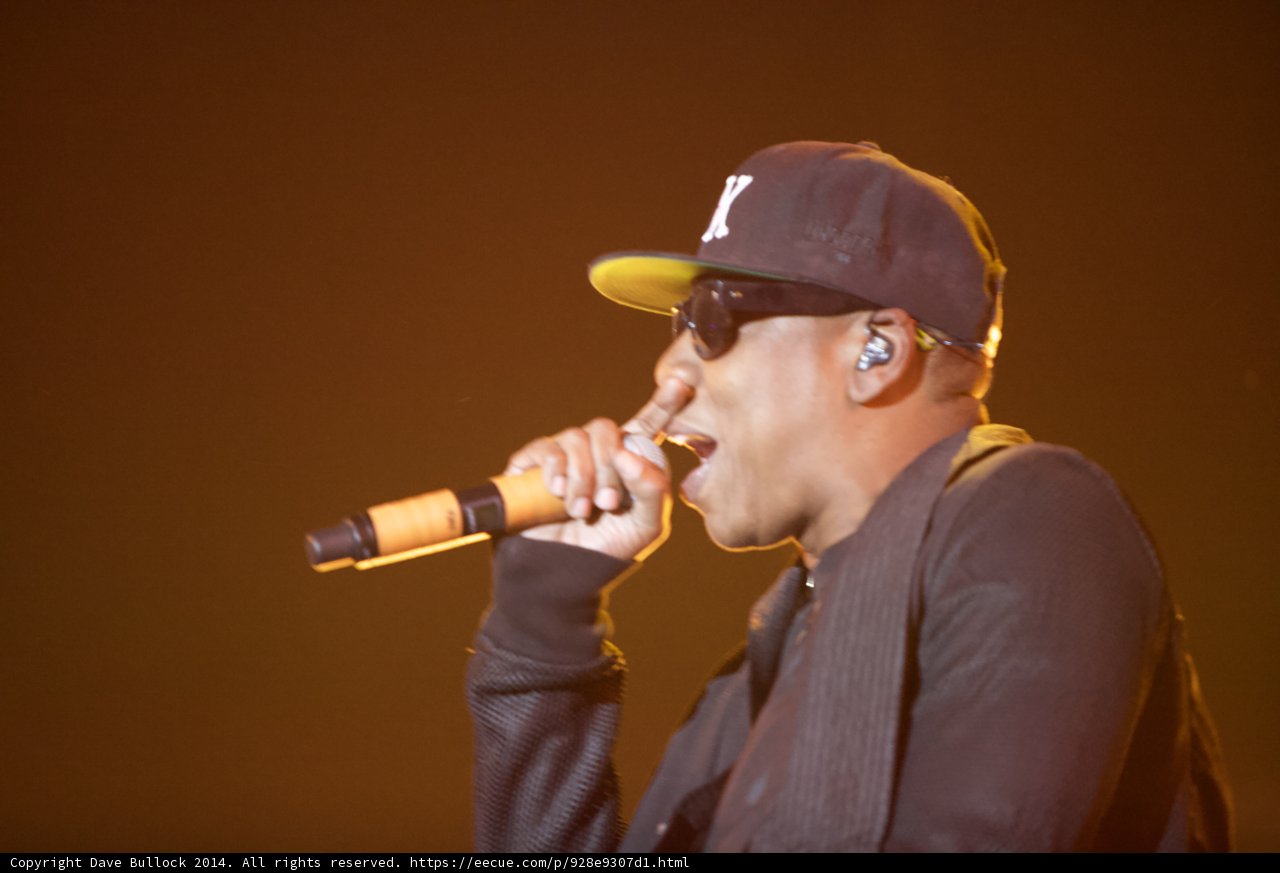 Jay-Z rocks the Coachella stage with signature baseball cap Caption: Jay-Z electrifies the audience at Empire Polo Club sporting his trademark baseball cap while wielding a microphone and captivating the crowd.