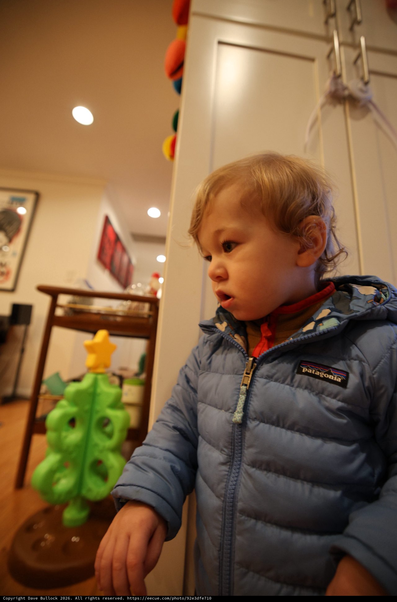 Toddler in Patagonia Jacket Gazing at Green Toy