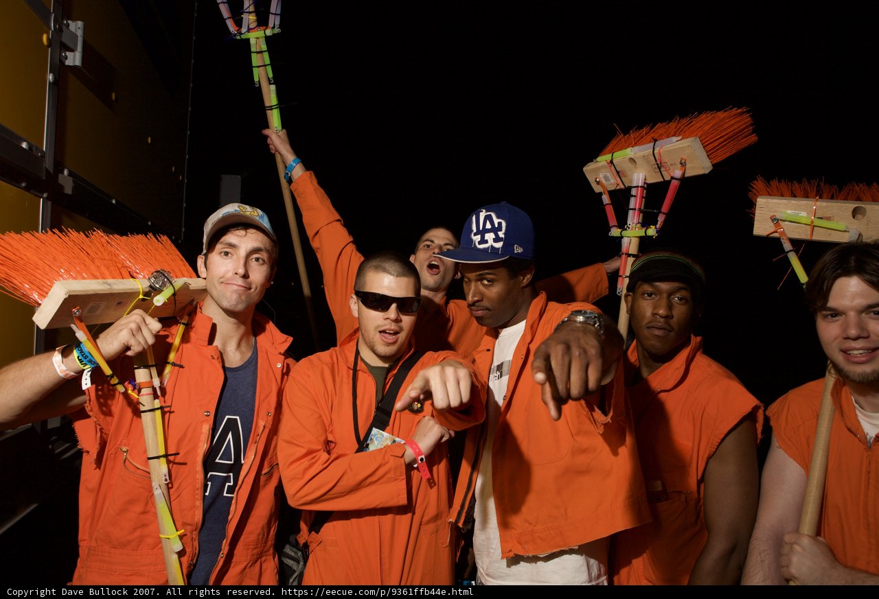 Men in Orange Outfits Holding Broom Sticks