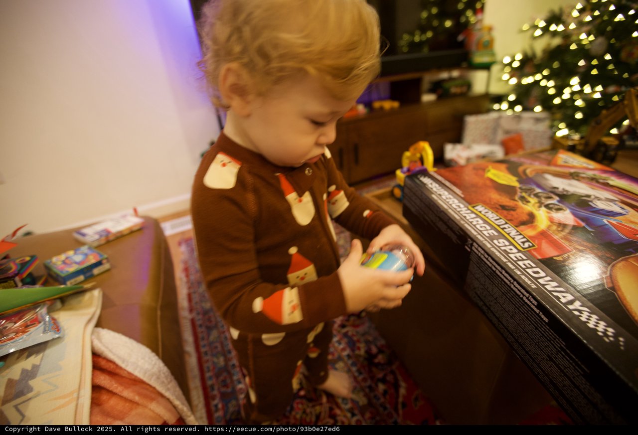 Toddler Opening Christmas Presents by Lit Tree