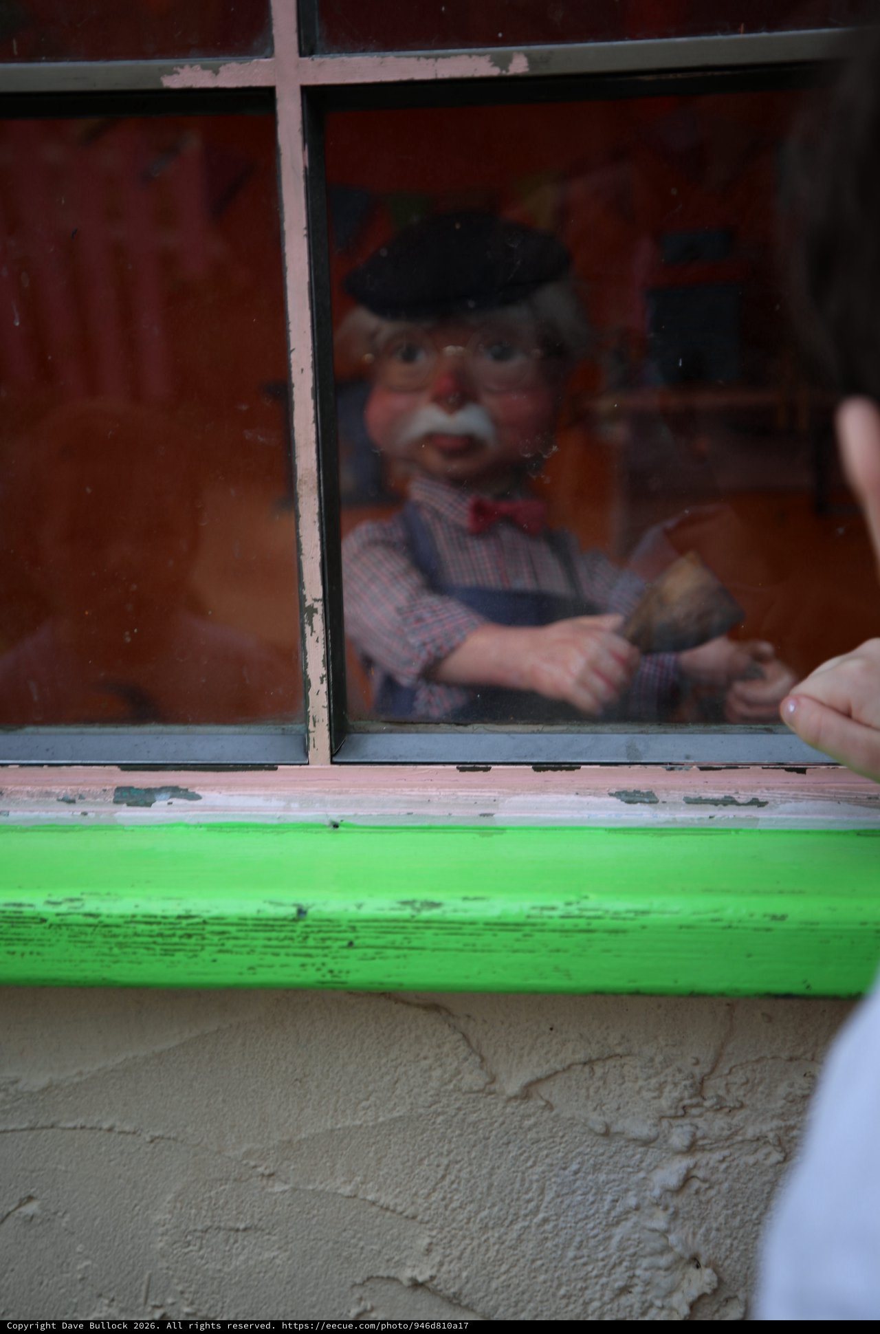Vintage Puppet Display Behind Weathered Green Window