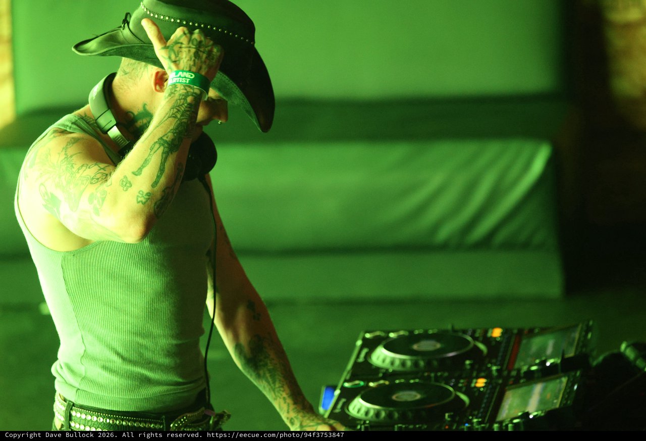 Tattooed DJ Spinning Under Green Lights at Wobbleland