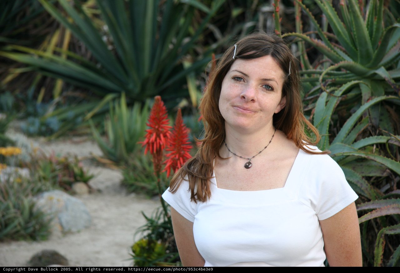 Woman Smiling Amid Desert Succulents and Aloe Blooms