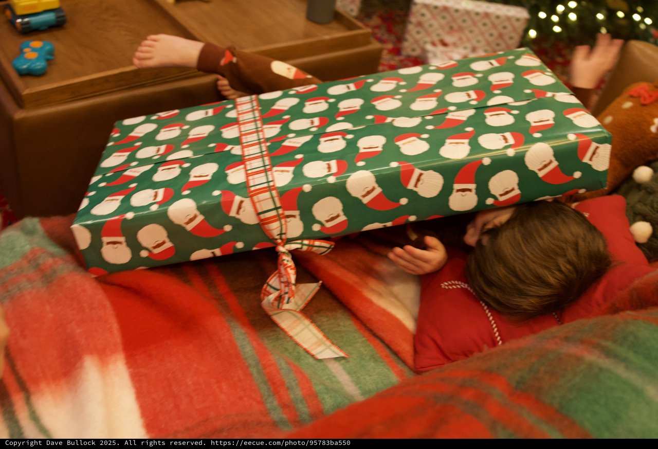 Child Opening Christmas Present with Santa Wrapping Paper