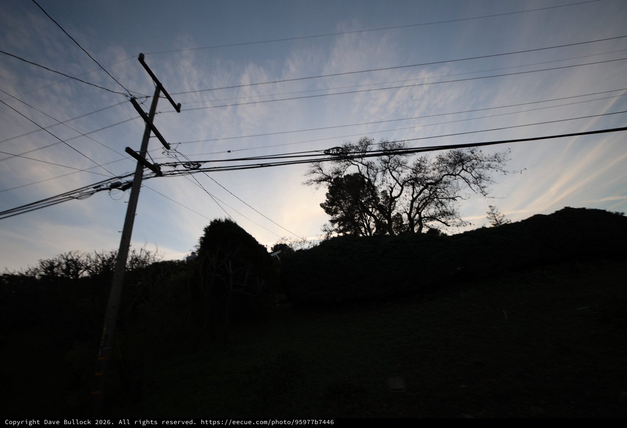 Silhouetted Power Lines at Dusk Over Rural Hillside