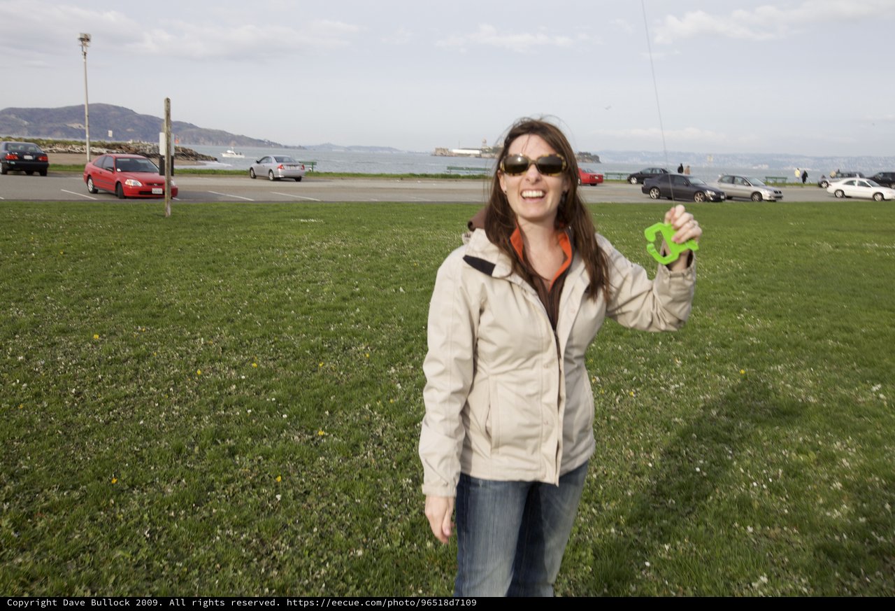 Joyful Woman Holds Green Toy at San Francisco Waterfront