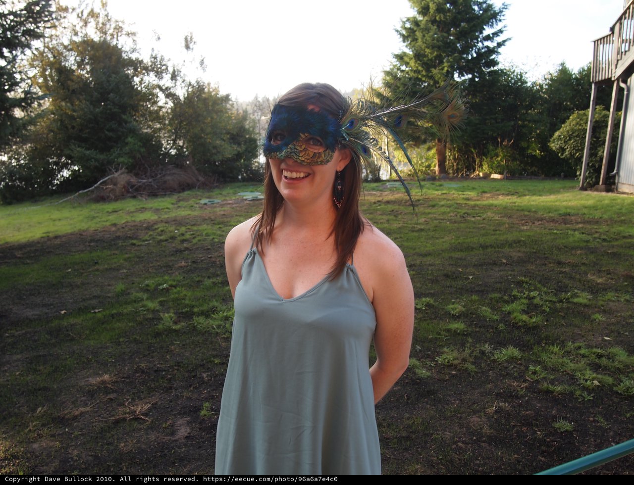 Smiling Woman in Peacock Masquerade Mask Outdoors